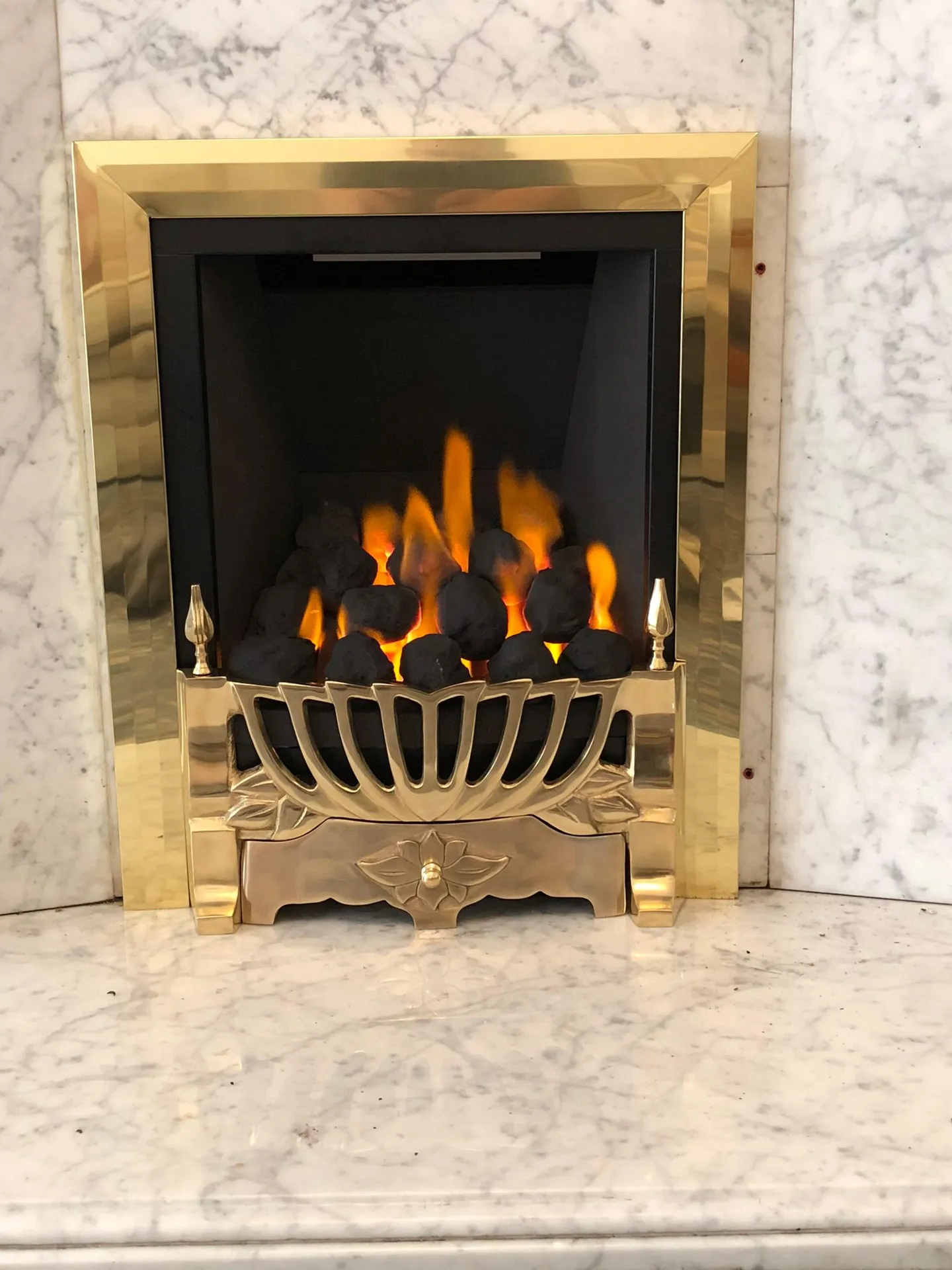 Gas fire with brass surround installed in a marble fireplace