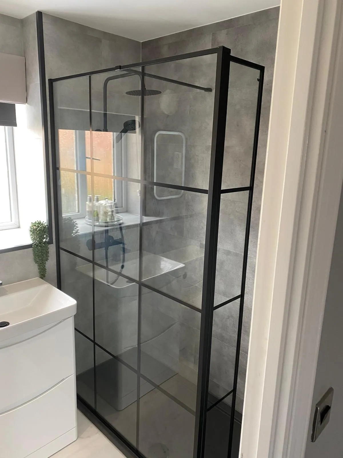 Walk-in shower with black grid-framed glass screen and grey tiles in North Shields
